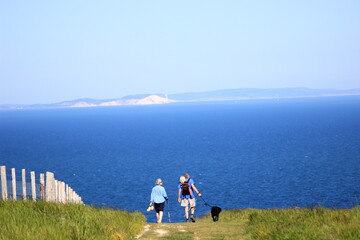 old couple of hikers with a dog walking on the cliffs on the coast of england united kingdom