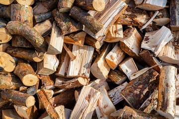 A firewood stacked in a pile, lying in the sun, close up shot, wooden background.