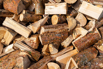 A firewood stacked in a pile, lying in the sun, close up shot, wooden background.