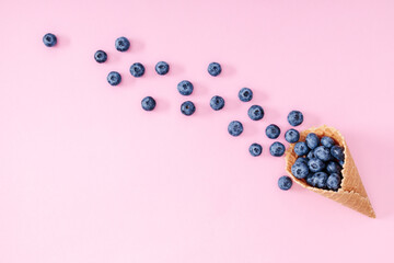 Fresh berries blueberries in waffle cone on pastel pink background. Summer background. Creative berries concept. Flat lay, top view, copy space