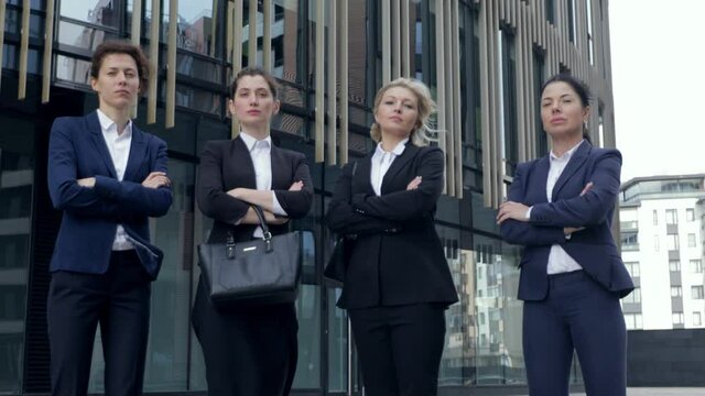 Four serious successful business women are standing with crossed arms. Looking at camera, ready to sing big contract. Moving dynamic camera. Gander equality, parity, High quality 4k footage