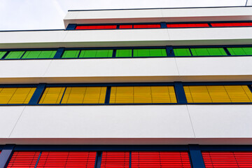 Elevation of a modern office building with different colors of blinds on each floor.