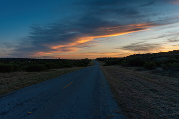 Band of gray and orange clouds glowing over rural country road