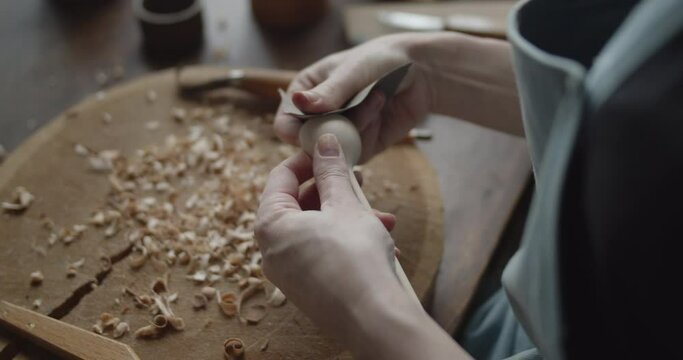 Woman carpenter polishes wooden spoon with a sandpaper close-up
