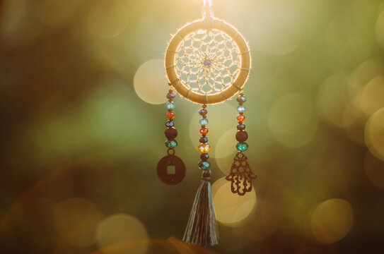 Close up of spiritual dreamcatcher necklace with sacred geometry circle with bokeh background backlit by sunset golden light