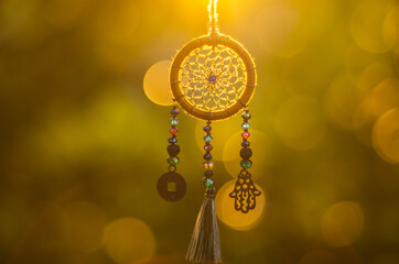 Close up of spiritual necklace with sacred geometry circle with bokeh background backlit by sunset golden light