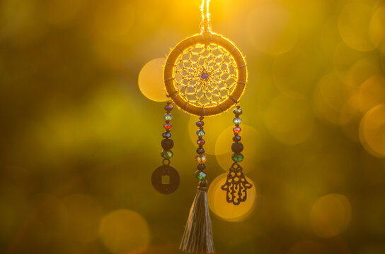 Close up of spiritual necklace with sacred geometry circle with bokeh background backlit by sunset golden light
