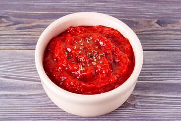 Spicy tomato or paprica sause or traditional balkan sause ajvar in a bowl on a wooden background. Vegan food.