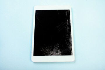 Broken white tablet on blue background, broken glass needs repair