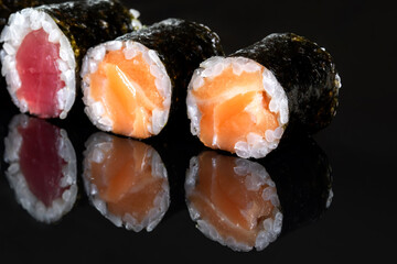 Rolls with salmon, rice, nori, fresh salmon. Several rolls are in one row.