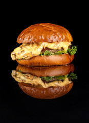 Hamburger with chanterelle mushrooms, on black isolated background. Reflection in a black mirror. Vertical photography.