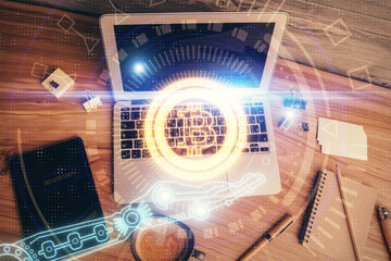 Blockchain theme hologram drawings over computer on the desktop background. Top view. Multi...