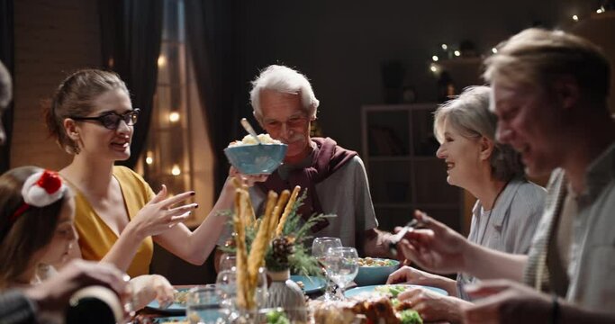Happy large caucasian family of different generations celebrating christmas at home. People having a dinner xmas party eating, talking and smiling 4k footage
