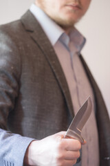 Male hand of a business man holds a knife.