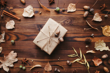 Autumn creative holiday present. Handmade paper gift box with foliage dried leaves, pine cones and acorns. Thanksgiving day, fall background. Copy space