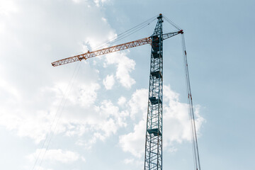 construction crane on the background of a new residential area and cloudy beautiful sky