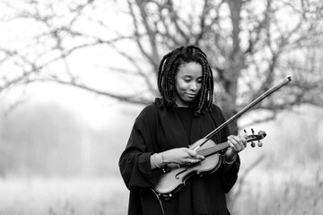 Portrait of black woman musician with violin in nature