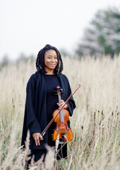 Portrait of black woman musician with violin in nature