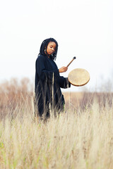 Portrait of black woman musician with tambourine in nature