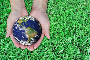 Earth day concept. Globe in hand on green lawn background. Elements of this image furnished by NASA