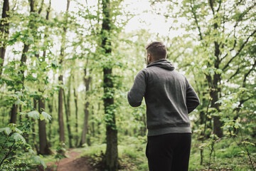 Fototapeta na wymiar Adult sporty man in forest, park running in the morning