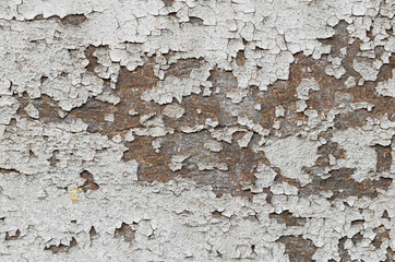 The texture of an old painted wall of white color and peeling spots.