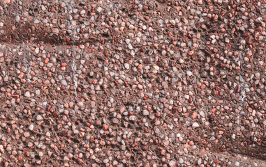 The texture of small pebbles of brown white color in cement. Brown stone background.