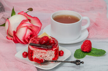 Raspberry cheesecake with mint and pink rose on a white table, close-up side view.