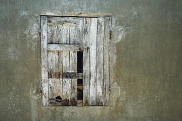Broken wooden shutter in weathered wall with room for text
