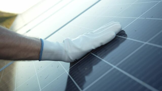 Hand of workman in white gloves touching the solar panel batter to check its cleanliness. Renewable energy. Solar power generation. Electricity. Bio ecology.