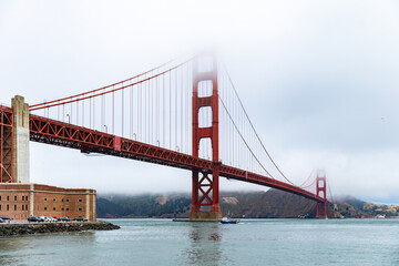 famous red suspension bridge in a city with low clouds