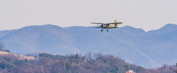 Fototapeta na wymiar Biplane flying over mountainous region