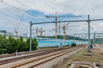 Fototapeta na wymiar Railroad tracks and tall yellow construction cranes