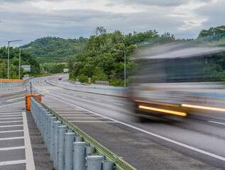 Streaks of light and blur of passing vehicle on highway in countryside location during blue hour under cloudy skies.