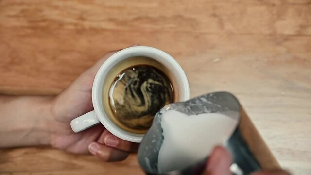 Close-up view of a barista demonstrating the art of pouring and preparing a cup of coffee. Making latte art. High quality FullHD footage.