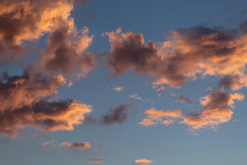 Beautiful orange, violet and white clouds at evening with blue sky at background. 