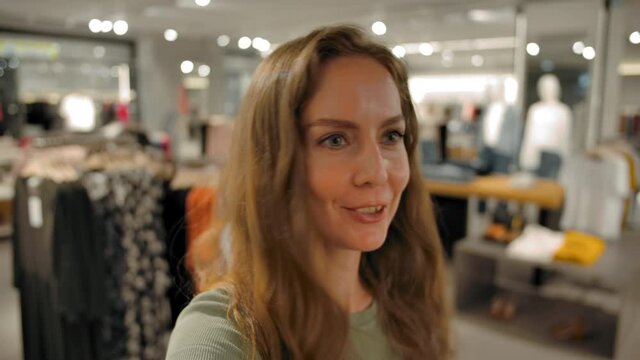Woman recording video stories on socials or have an online conversation with her friends. POV view of beautiful caucasian female shopping in fashionable slothes store.
