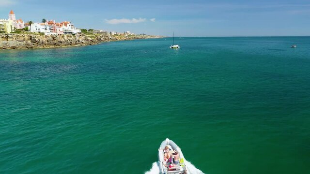 Aerial, drone shot over a rib boat, driving on the coast of Cascais, sunny day, in Portugal