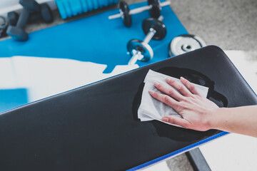 the new normal after covid-19, hand cleaning gym equipment with disinfectant wipe against virus and...