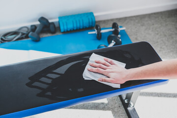the new normal after covid-19, hand cleaning gym equipment with disinfectant wipe against virus and...