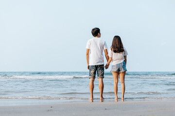 Romantic couple holding hands and stand together on beach. Man and woman in love.