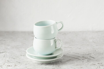 two empty porcelain light blue cups in Oriental style and two saucers stand in each other on a light concrete background