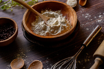 flour, sugar and chocolate granules for preparation of making bread on Indonesian traditional cutlery set or tableware made of wood isolated on brown