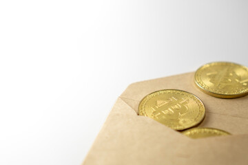 Top view of envelope with golden bitcoin coins as a gift. There are big golden BTC cryptocurrency coins on table.