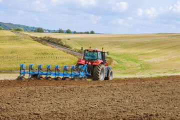 Plowing the field. Large plow on a tractor. Tractor with agricultural attachment.
