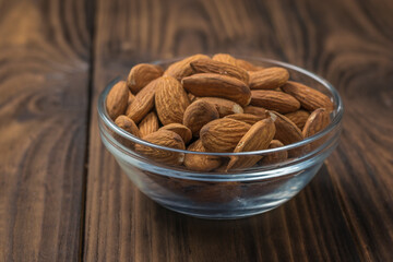 Large almonds in a glass Cup on a wooden table.