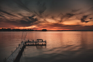 Fototapeta na wymiar Sunset on lake overlooking a boat and fishing dock