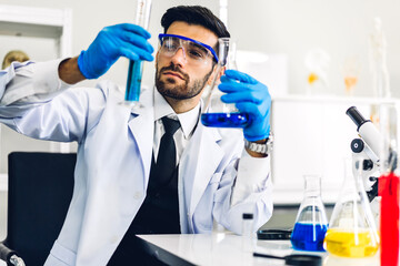 Professional scientist man research and working doing a chemical experiment while making analyzing and mixing  liquid in test tube.Young science man looking sample chemical on glass at laboratory