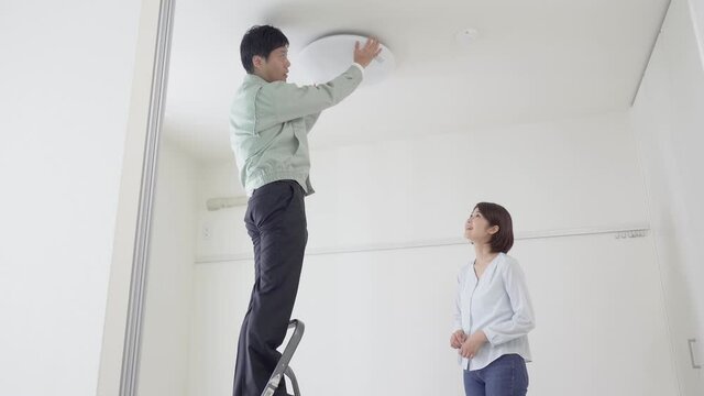 天井にシーリングライトを取り付ける作業員