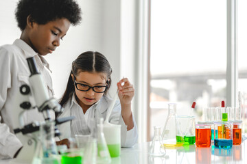 Group of teenage cute little students child learning research and doing a chemical experiment while making analyzing and mixing liquid in test tube at experiment laboratory class at school.Education